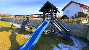a playground with a blue slide in a yard at Domki Premium Nad Bałtykiem in Wodnica