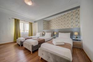a hotel room with two beds and two tables at Sliema Seaview 4BD Apartments & Penthouse with Jacuzzi in Sliema