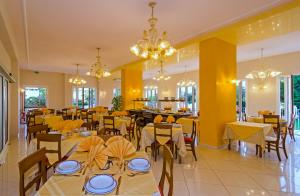 a restaurant with tables and chairs with yellow walls and chandeliers at Hotel Lido in Marina di Massa