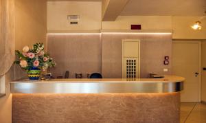 a lobby with a counter with a vase of flowers at Hotel Lido in Marina di Massa +33 photos