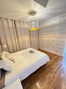 a bedroom with a white bed and a chandelier at Large house with garden in Vulaines-sur-Seine