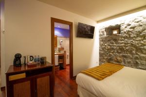 a bedroom with a bed and a stone wall at HOTEL EL Alboroque in Tramacastilla de Tena