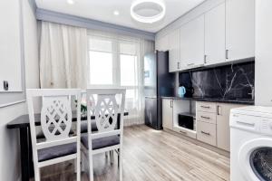 a kitchen with white cabinets and a table and chairs at Однокомнатные и 2х комнатные квартиры на Туране in Taldykolʼ