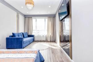 a living room with a blue couch and a tv at Однокомнатные и 2х комнатные квартиры на Туране in Taldykolʼ