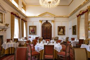 a dining room with tables and chairs and a chandelier at Hintlesham Hall Hotel in Ipswich