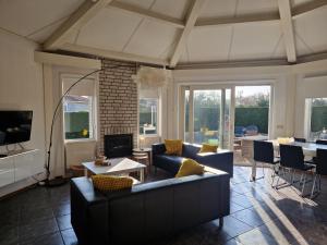 a living room with a couch and a table and chairs at De Golfakker in Hollum