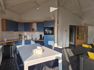 a kitchen with blue cabinets and a white table at De Golfakker in Hollum