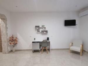 a white room with a desk and a tv on a wall at ASTRA Guest House in Taranto