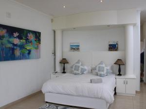 a white bedroom with a bed and a painting on the wall at Villa Aurora in Margate