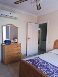 a bedroom with a bed and a dresser and a mirror at Lazorde Bay Apartment in El Alamein +22 photos