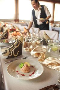 a table with a plate of food and a man in a restaurant at Hotel Hrádok in Jelšava