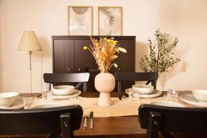 a dining room table with a vase of flowers on it at Gemütliches Apartment mit Garten nahe Köln in Frechen +13 photos