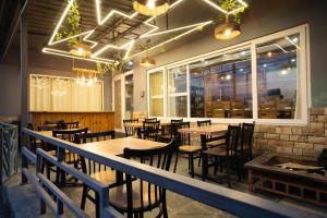 a restaurant with wooden tables and chairs and windows at Hotel Buddha House Himalayan Brothers in Dharamshala