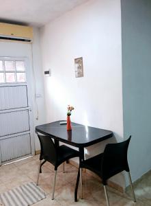 a black table with two chairs and a vase with flowers at Departamento J&J 2 in Aristóbulo del Valle