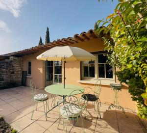 a patio with a table and chairs and an umbrella at Mas la Provence in L'Isle-sur-la-Sorgue