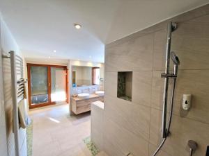 a bathroom with a shower and two sinks and a tub at Tanne Tonbach - Wellness & Wohlfühl Hotel in Baiersbronn