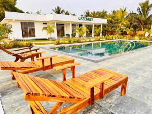 a pool with wooden benches in front of a building at GreenKey Hotel & Resturent in Tanamalwila