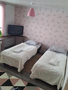 a bedroom with two beds and a tv on a wall at MarrasVilla in Marrasjärvi