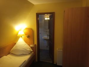 a bedroom with a bed and a bathroom with a sink at Hotel Büker in Erwitte