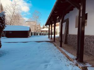 a snow covered yard with a building with a roof at Shiro Lodge in Predeal