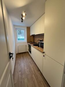 a kitchen with white cabinets and a wooden floor at Shiro Lodge in Predeal