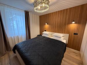 a bedroom with a bed with a black blanket and a chandelier at Shiro Lodge in Predeal