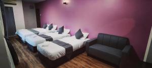 a room with three beds and a chair at City Hub Hotel Sitiawan in Sitiawan