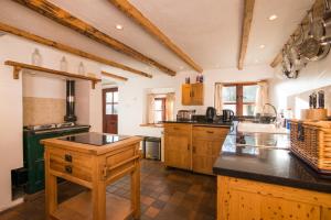 a large kitchen with wooden cabinets and a black counter top at Colourmill cottage in Leek