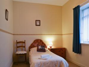 a bedroom with a bed and a chair and a window at Macdonald Cottage in Balnald