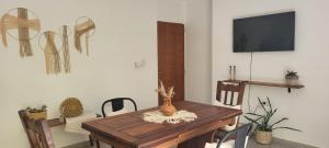 a dining room with a wooden table with chairs and a television at CasaMora departamento céntrico con cochera gratis, 2 habitaciones in Almafuerte