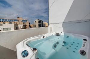 a bath tub on a balcony with a view of a city at Sliema Seaview 4BD Apartments & Penthouse with Jacuzzi in Sliema