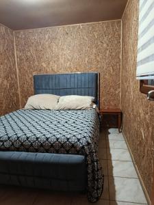 a bed in a room with a blue bed frame at cabaña vale in Coñaripe