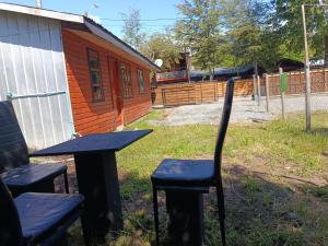 a table and chairs in front of a building at cabaña vale in Coñaripe