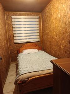 a small bedroom with a bed and a window at cabaña vale in Coñaripe
