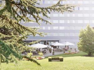 a building with tables and umbrellas in a park at Novotel Suites Genève Aéroport in Geneva