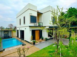 a house with a swimming pool in front of it at Mimi Pool Villa Chiangmai in Chiang Mai