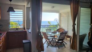 a kitchen with a table and chairs and a view of the ocean at Le chant du Diamant calme vue mer et plage à 50 m in Le Diamant