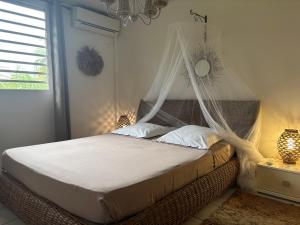 a bedroom with a bed with a mosquito net at Le chant du Diamant calme vue mer et plage à 50 m in Le Diamant