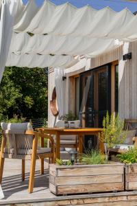 a wooden table and chairs under a white umbrella at Wohnwagon BALU in Apetlon