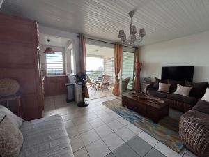 a living room with a couch and a table at Le chant du Diamant calme vue mer et plage à 50 m in Le Diamant