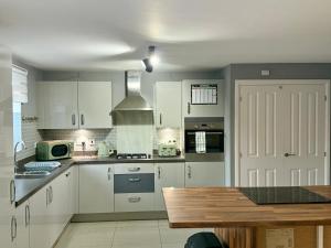 a kitchen with white cabinets and a stove top oven at Chislehurst House in Bedford