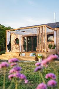 a wooden house with a porch and purple flowers at Wohnwagon BALU in Apetlon +46 photos