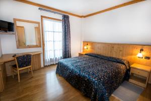 a bedroom with a bed and a desk and a window at Hotel Giardino in Bormio
