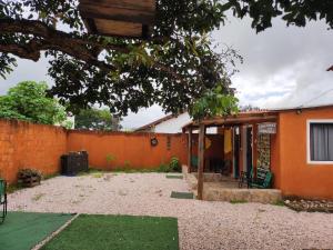 a house with an orange wall and a yard at Cantinho da Lobeira in Alto Paraíso de Goiás