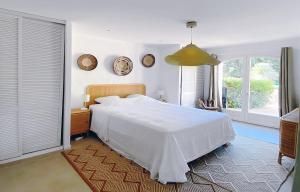a bedroom with a white bed and two windows at Luxury Villa, Infinity Pool, Beach 5 min in Ramatuelle