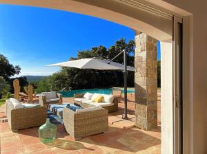 a patio with chairs and an umbrella and a pool at Luxury Villa, Infinity Pool, Beach 5 min in Ramatuelle