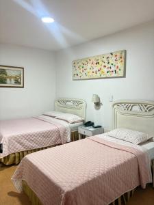 two beds in a room with white walls at Hotel Chucarima in Cúcuta