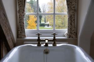 a white bath tub in front of a window at Hintlesham Hall Hotel in Ipswich