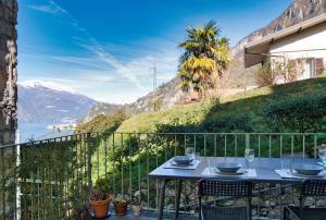 a table on a balcony with a view of a mountain at Casa Rosa - hidden Garden with lake view in Fiumelatte