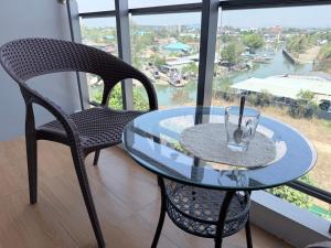 a glass table and chairs in a room with a window at Whale Marina Condo in Na Jomtien